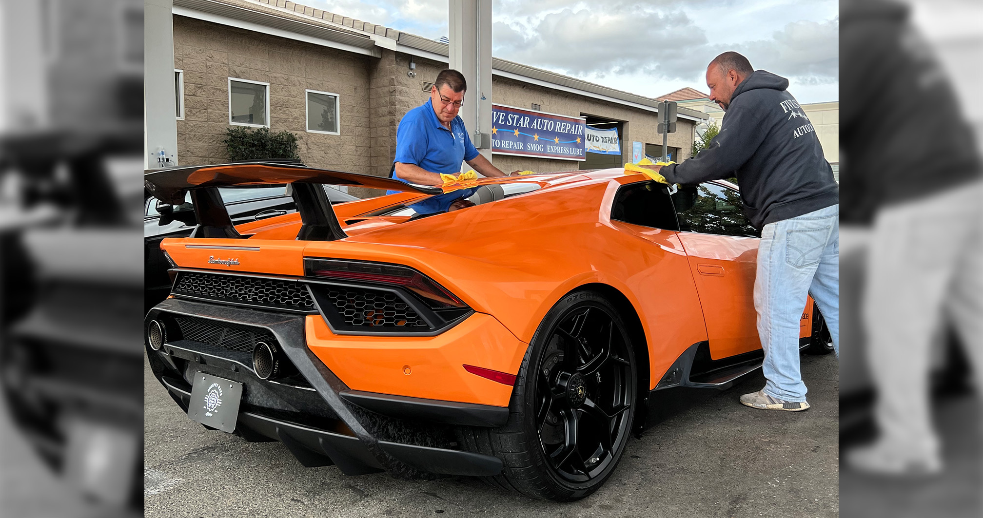 A bright orange Lamborghini Huracán being carefully hand-detailed by two auto care professionals.